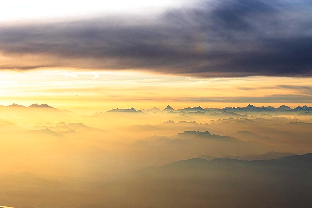 Flying over the majestic Swiss Alps in a sea of clouds at sunset, Switzerland