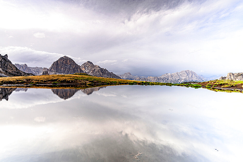 Bright sky at dawn over Monte Cristallo and Tofane mountains mirrored in water, Giau Pass, Dolomites, Veneto, Italy, Europe