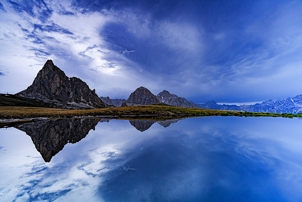 Ra Gusela and Tofane mountain peaks reflected in water under the cloudy sky at dusk, Giau Pass, Dolomites, Veneto, Italy, Europe