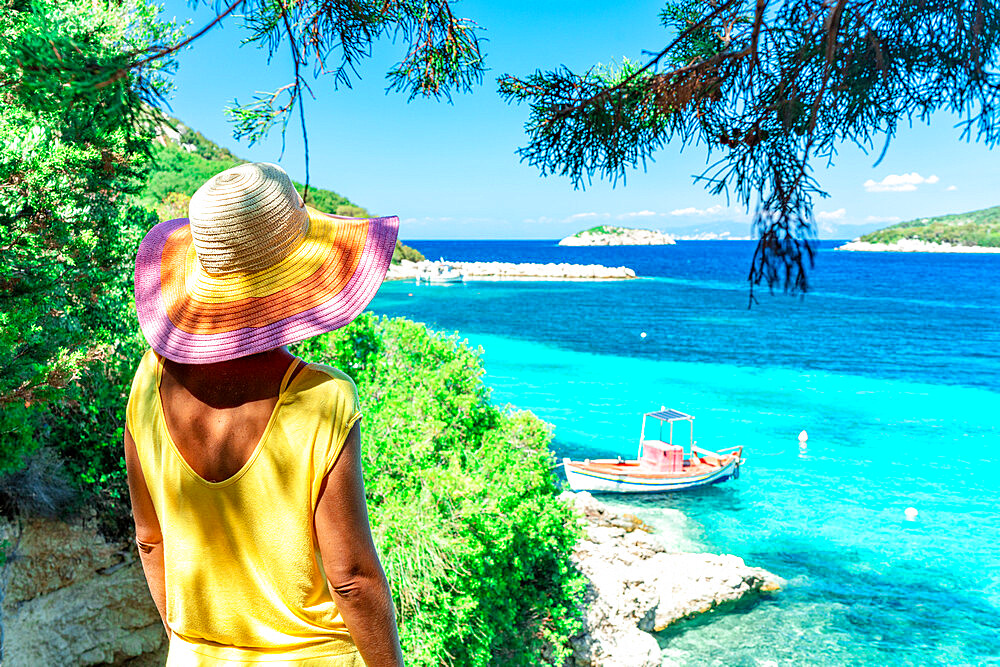 Woman contemplating the crystal sea standing under the trees in shadow on hill, Porto Atheras, Kefalonia, Ionian Islands, Greek Islands, Greece, Europe