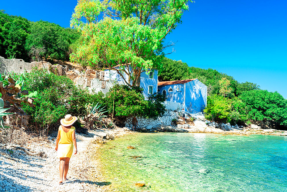 Woman walking on white pebbles of a beach surrounded by trees, Porto Atheras, Kefalonia, Ionian Islands, Greek Islands, Greece, Europe