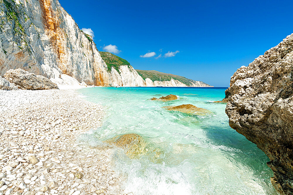 Waves of the turquoise clear sea washing the white stones of Fteri Beach, Kefalonia, Ionian Islands, Greek Islands, Greece, Europe