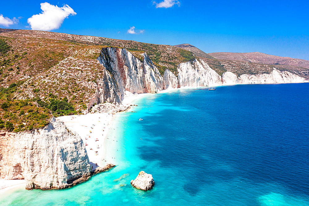 Tourists sunbathing at idyllic Fteri Beach set among cliffs and blue lagoon, overhead view, Kefalonia, Ionian Islands, Greek Islands, Greece, Europe