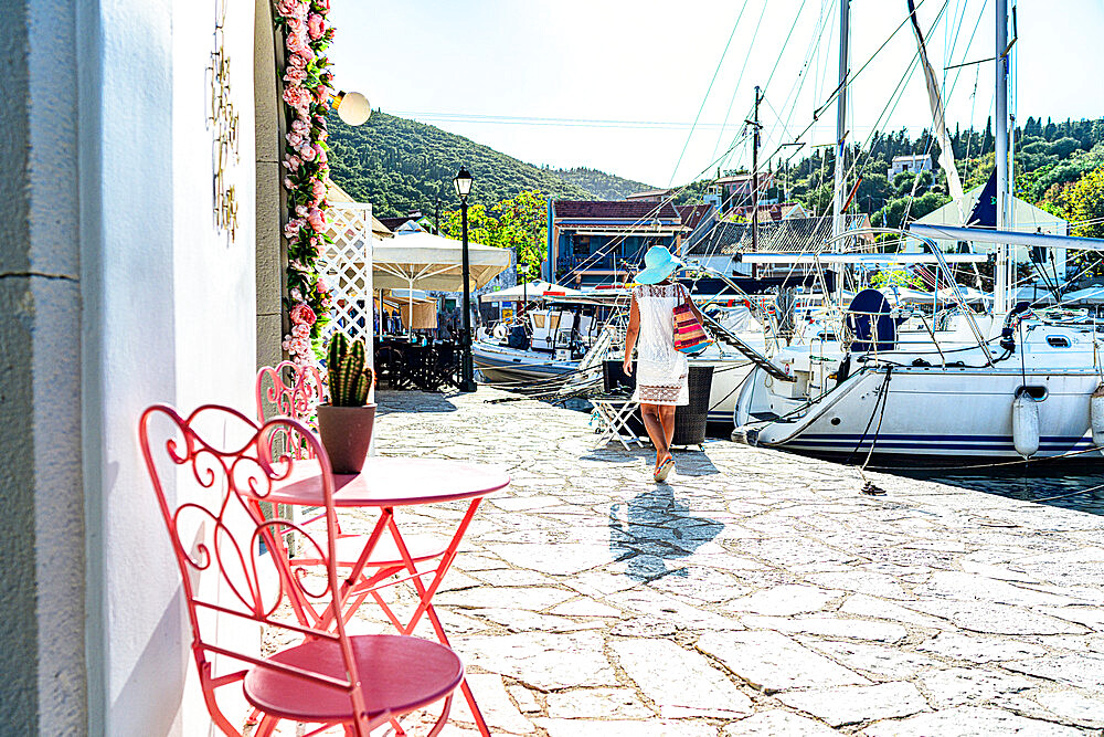 Woman looking at sailboats in the small harbor of the coastal village of Fiskardo, Kefalonia, Ionian Islands, Greek Islands, Greece, Europe