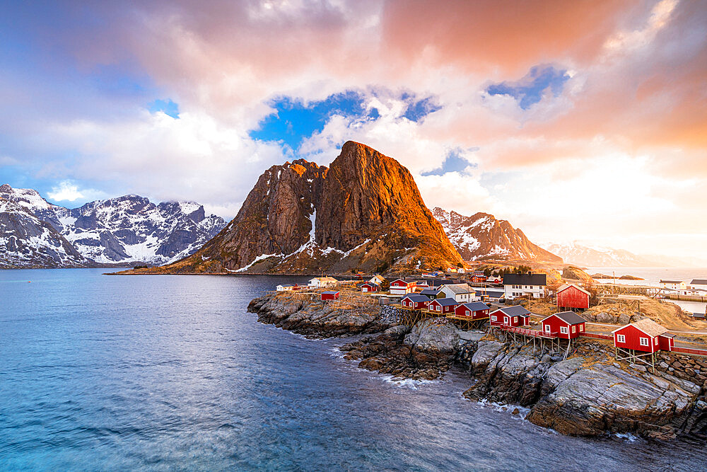 Clouds at sunrise over traditional Rorbu cottages on cliffs by the cold arctic sea, Hamnoy, Reine, Lofoten Islands, Norway, Europe