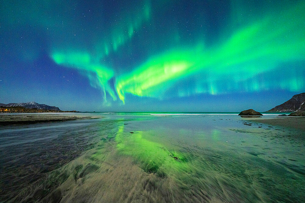 Starry night sky with Northern Lights (Aurora Borealis) reflected in the cold sea, Skagsanden beach, Ramberg, Nordland, Lofoten Islands, Norway, Scandinavia, Europe