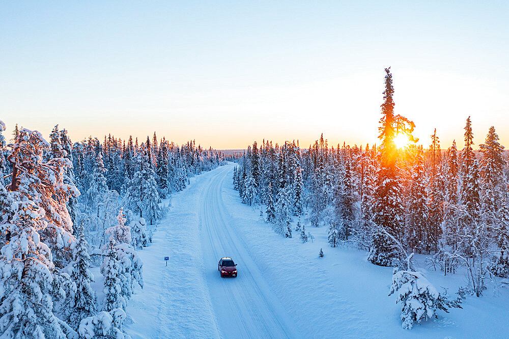 Car traveling on a snowy road in the frozen forest at sunrise, aerial view, Kangos, Norrbotten County, Lapland, Sweden, Scandinavia, Europe