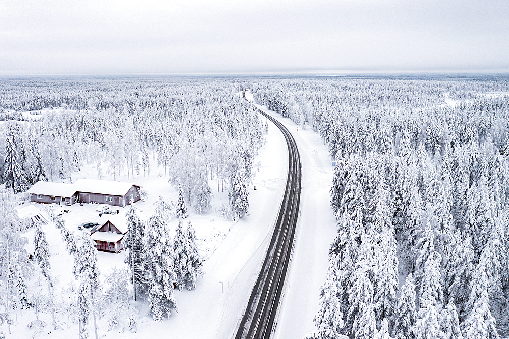 Winding road crossing the frozen snowy forest, aerial view, Lapland, Finland, Europe