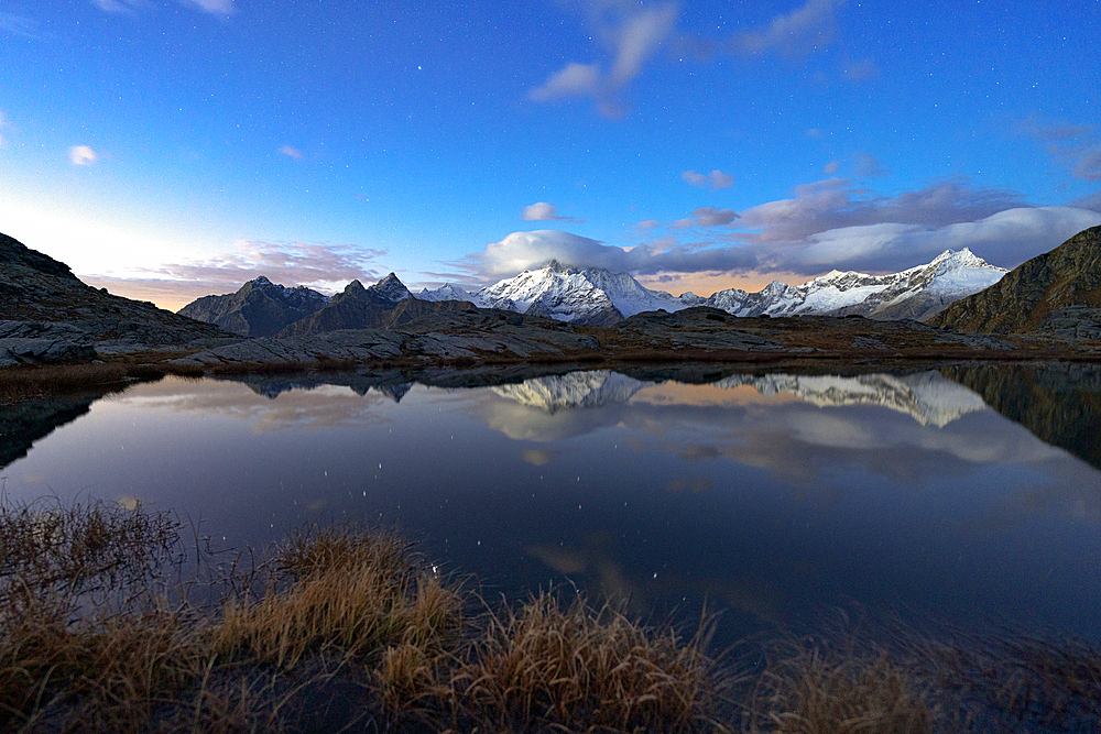 Snowy peak of Monte Disgrazia reflected in water at night, Alpe Fora, Valmalenco, Valtellina, Sondrio province, Lombardy, Italy, Europe