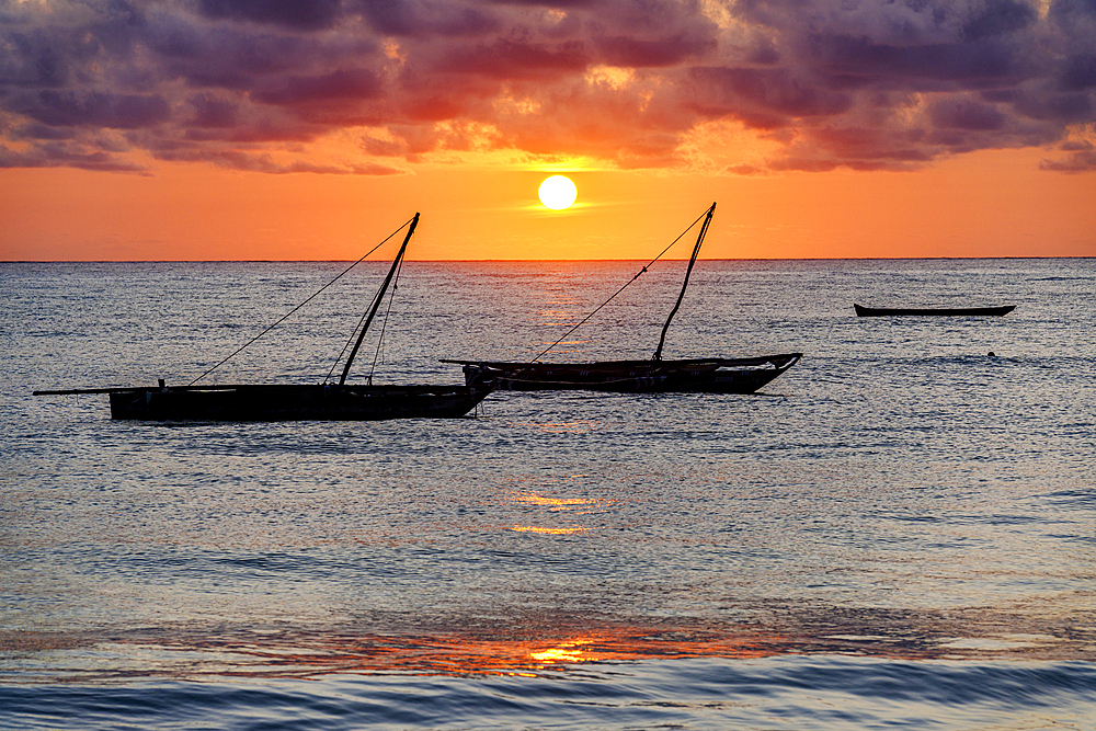 Cloudy sky at sunrise over silhouettes of boats moored in the sea, Jambiani, Zanzibar, Tanzania, East Africa, Africa