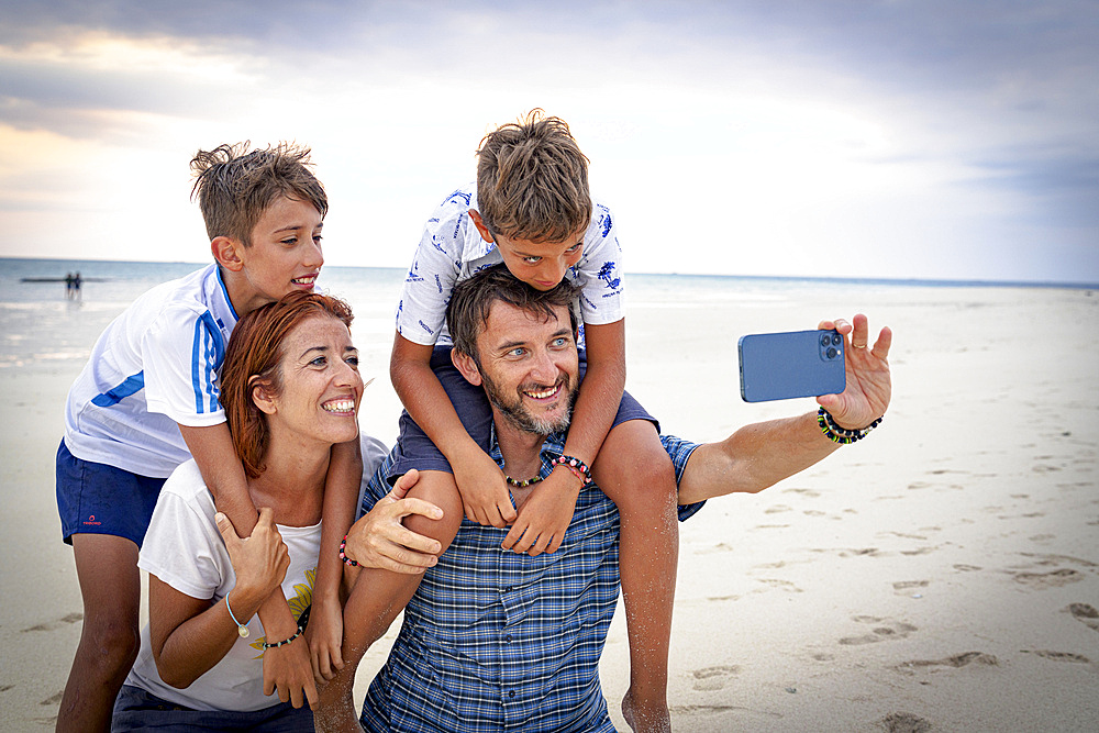 Happy family with two boys snapping a selfie with smartphone on a beach, Zanzibar, Tanzania, East Africa, Africa