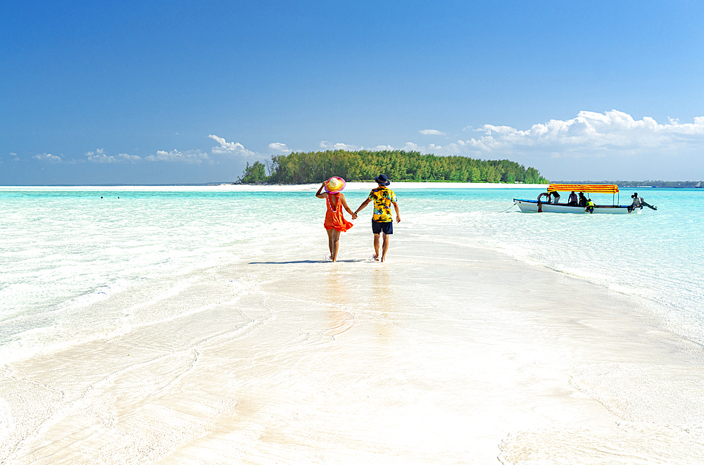 Man and woman in love holding hands walking on empty sandy shore surrounded by the Indian Ocean, Zanzibar, Tanzania, East Africa, Africa