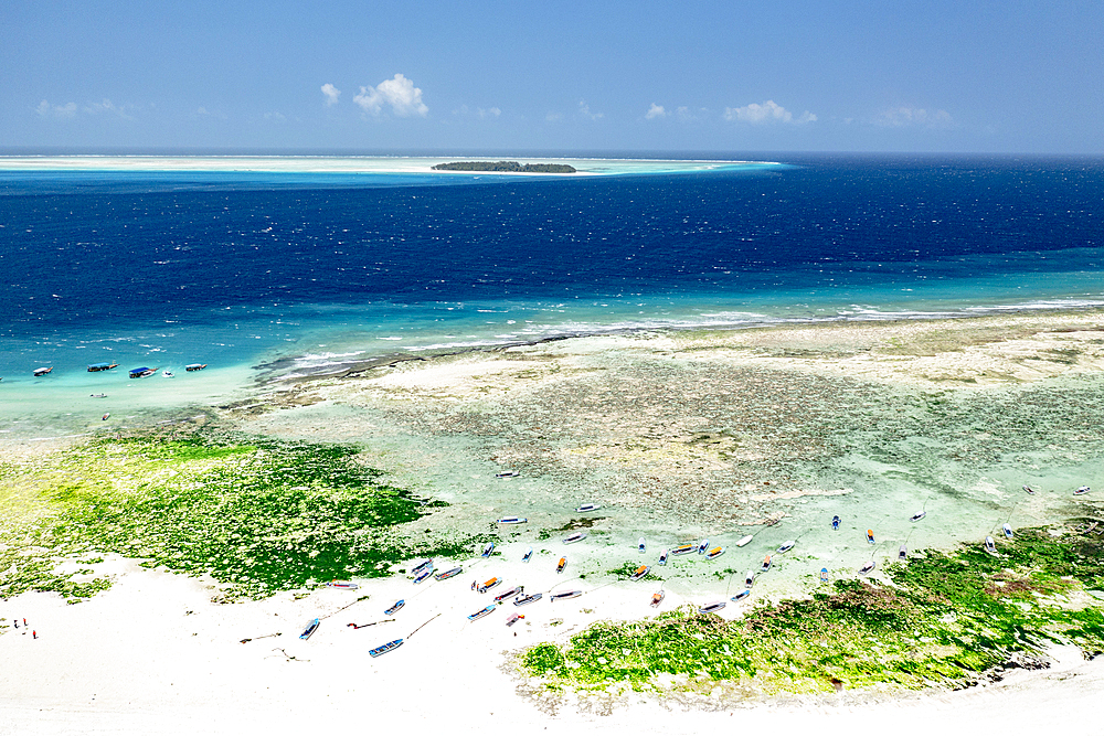 Boats on idyllic sand beach with Mnemba Island in the background, Zanzibar, Tanzania, East Africa, Africa