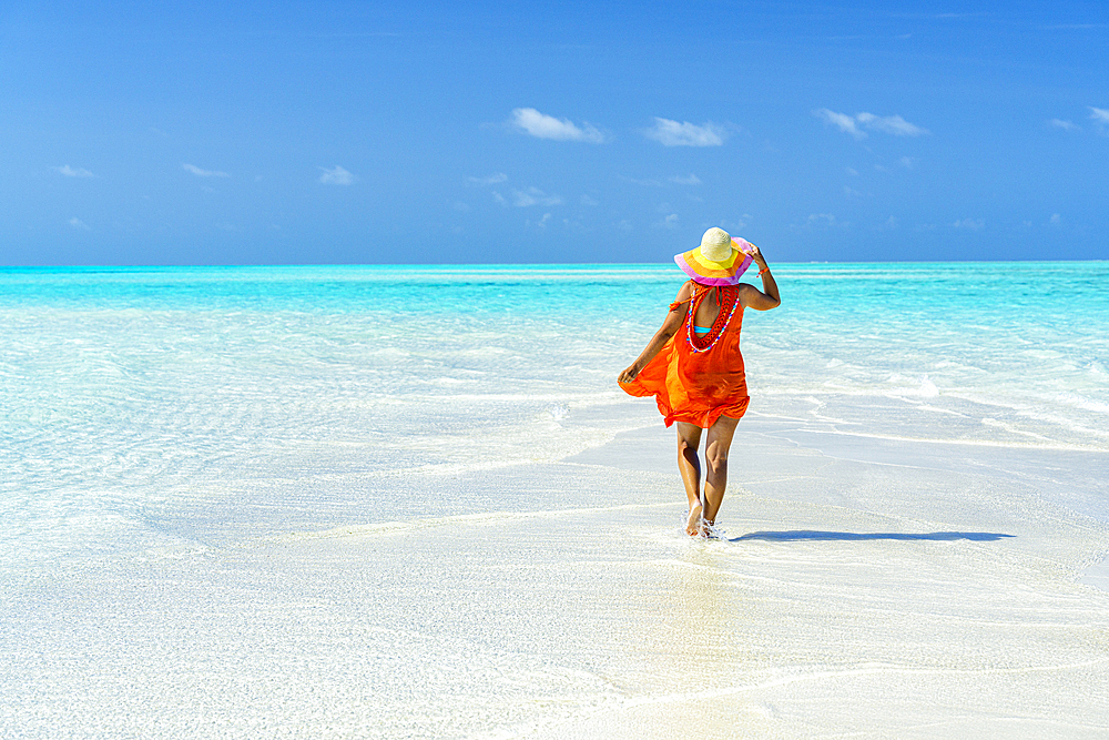 Woman with hat walking to the crystal clear sea, Zanzibar, Tanzania, East Africa, Africa