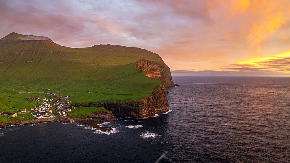 Fiery sky at dawn over the village of Gjogv ovelooking the ocean, aerial view, Eysturoy Island, Faroe Islands, Denmark, Europe