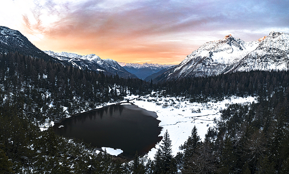 Aerial panoramic view of snowy forest and frozen lake Entova at sunrise, Valmalenco, Valtellina, Lombardy, Italy, Europe