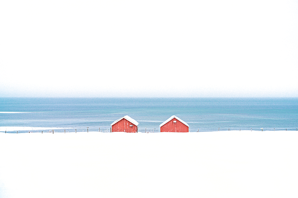 Red cabins in the snow overlooking the frozen sea, Troms county, Norway, Scandinavia, Europe