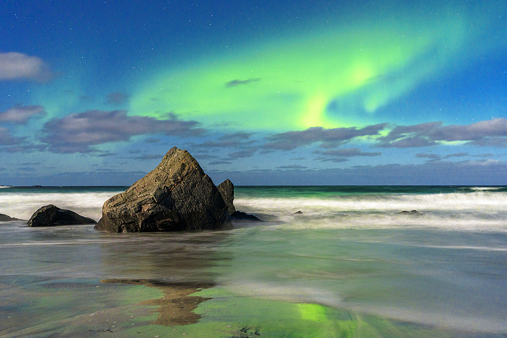 Waves crashing on rocks under a bright sky with te Aurora Borealis (Northern Lights), Skagsanden beach, Ramberg, Lofoten Islands, Nordland, Norway, Scandinavia, Europe