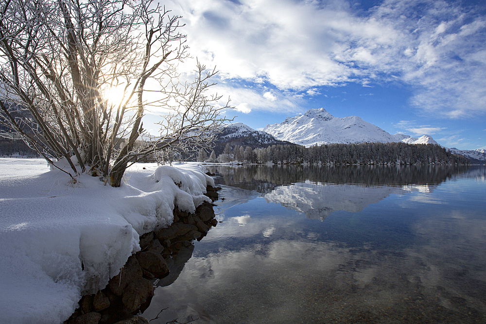 Snowcapped mountains reflected in the icy Lake Sils during a cold winter, Engadine, Canton of Graubunden, Switzerland, Europe