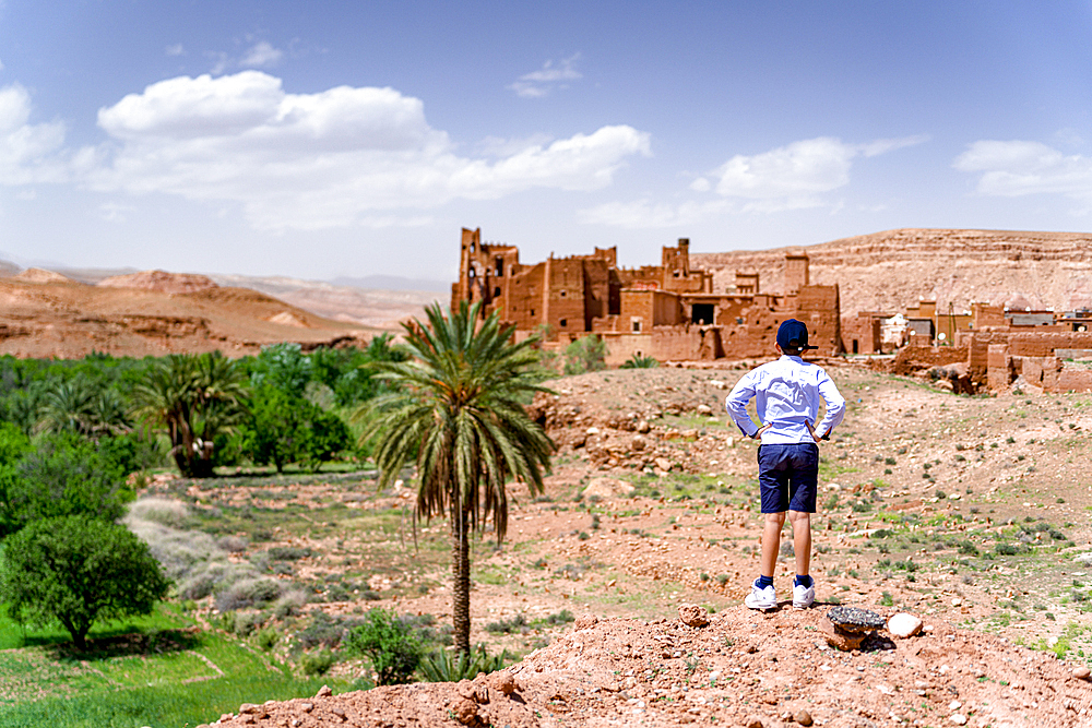 Rear view of boy admiring an old kasbah, Ounila Valley, Atlas mountains, Ouarzazate province, Morocco, North Africa, Africa