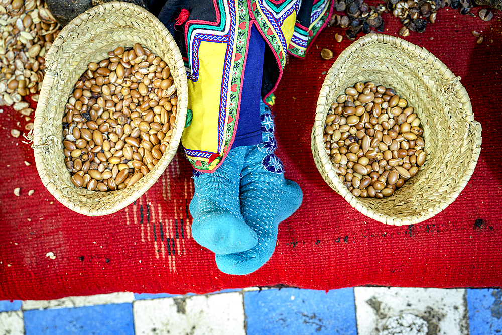 High angle view of worker resting beside straw baskets full of seeds for making argan oil, Morocco, North Africa, Africa