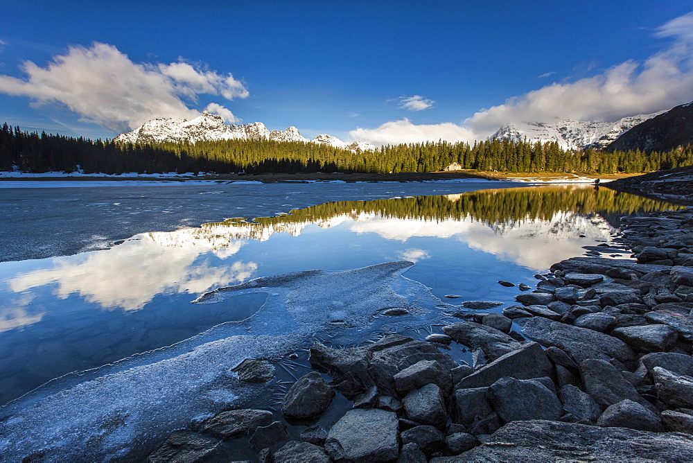 The spring thaw melts ice while snowy peaks are reflected in Lake Palu, Malenco Valley, Valtellina, Lombardy, Italy, Europe