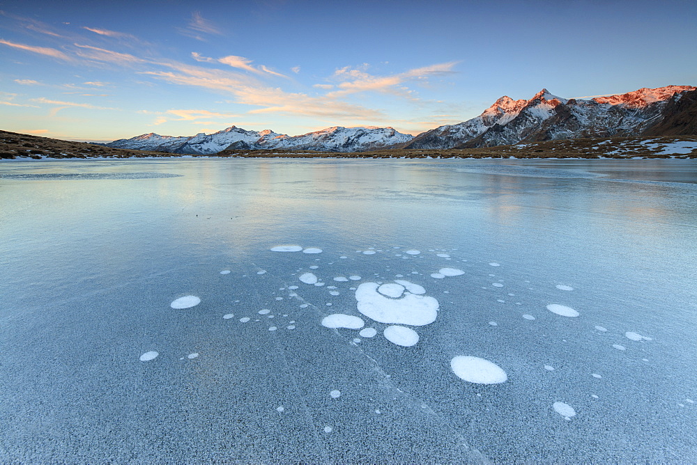 Ice bubbles on the frozen surface of Andossi Lake at sunrise, Spluga Valley, Valtellina, Lombardy, Italy, Europe