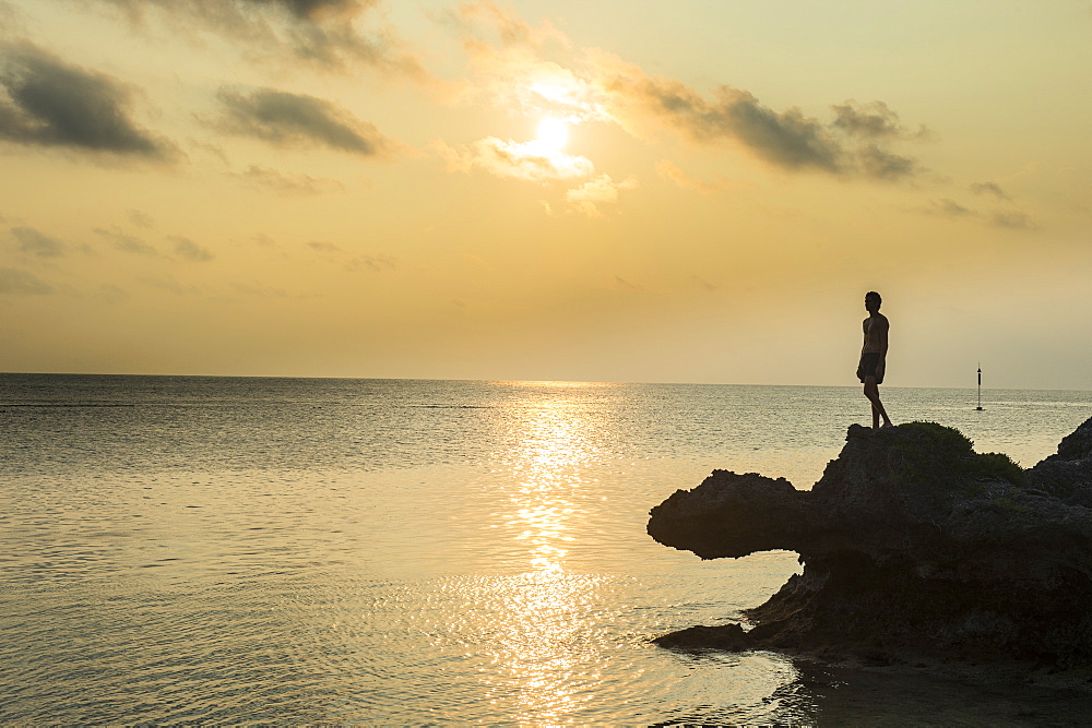 Man on a rock in backlight on the rocky west coast in Ouvea, Loyalty Islands, New Caledonia, Pacific