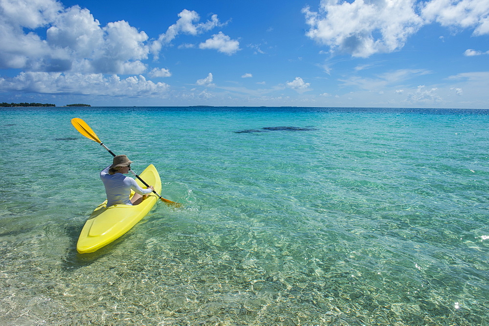 Woman kayaking in the turquoise waters of Tikehau, Tuamotus, French Polynesia, Pacific