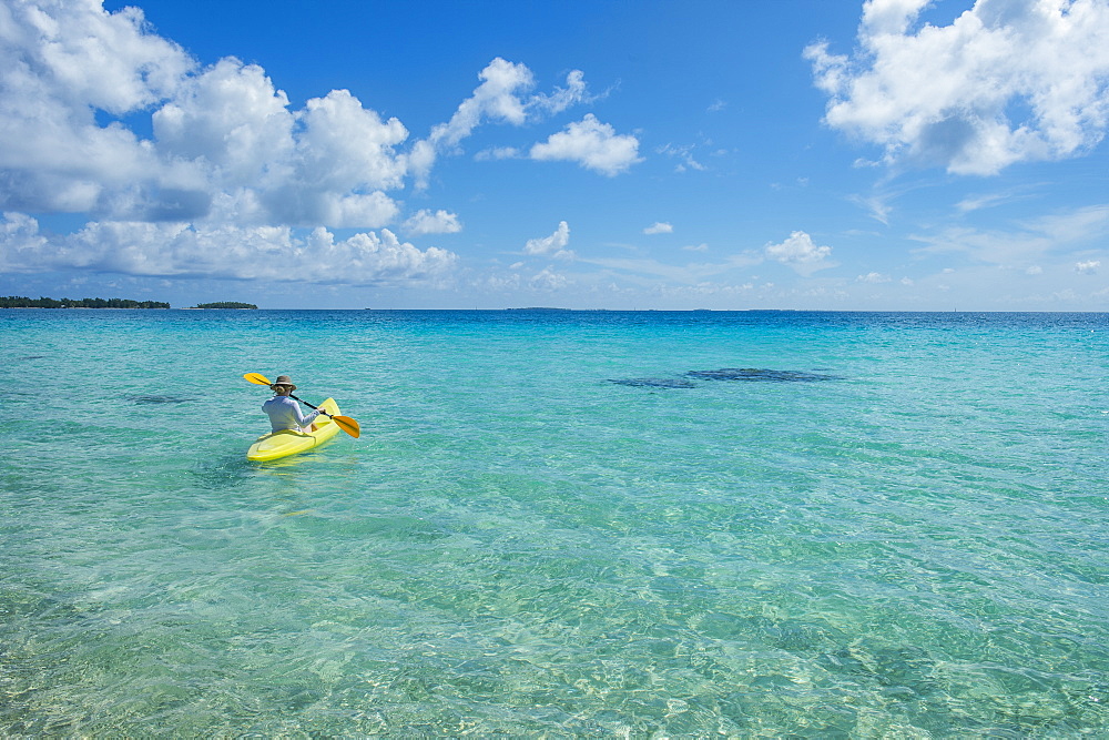 Woman kayaking in the turquoise waters of Tikehau, Tuamotus, French Polynesia, Pacific