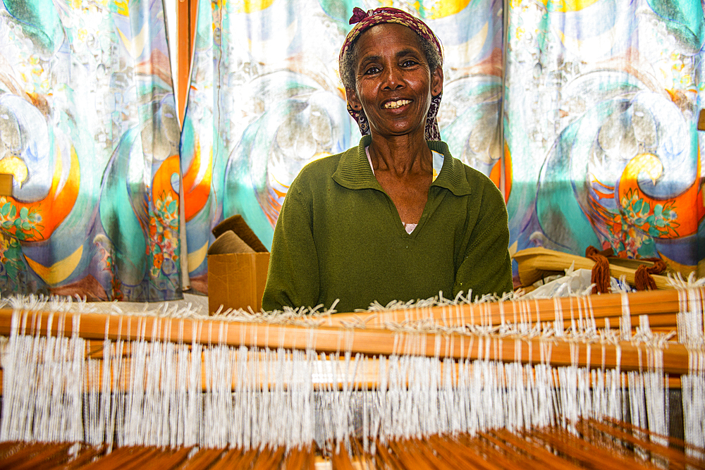 Friendly woman working on a hand weaving loom on a social project in the highlands of Eritrea, Africa