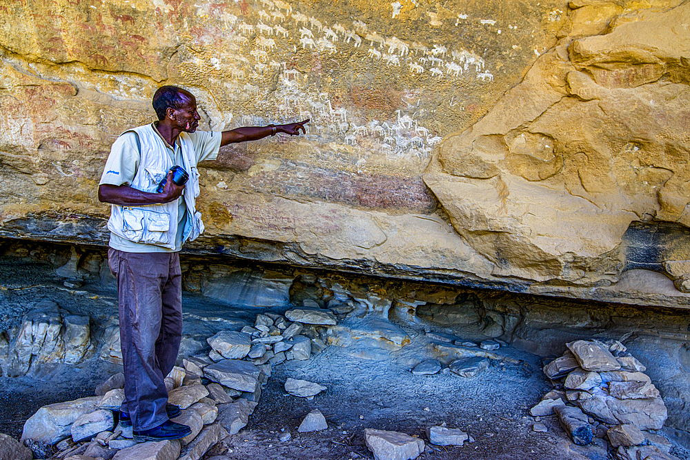 Guide pointing out ancient rock paintings at the Pre-Aksumite settlement of Qohaito (Koloe), Eritrea, Africa