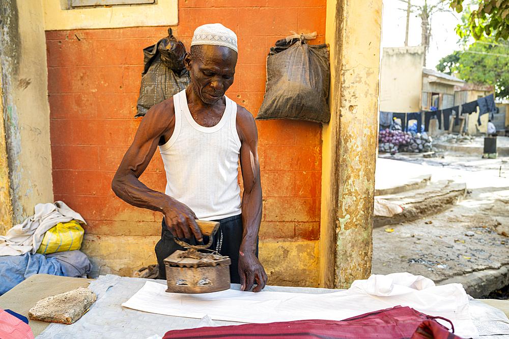 Man ironing with coal heatet iron, Kofar Mata Dye Pits, Kano, Nigeria