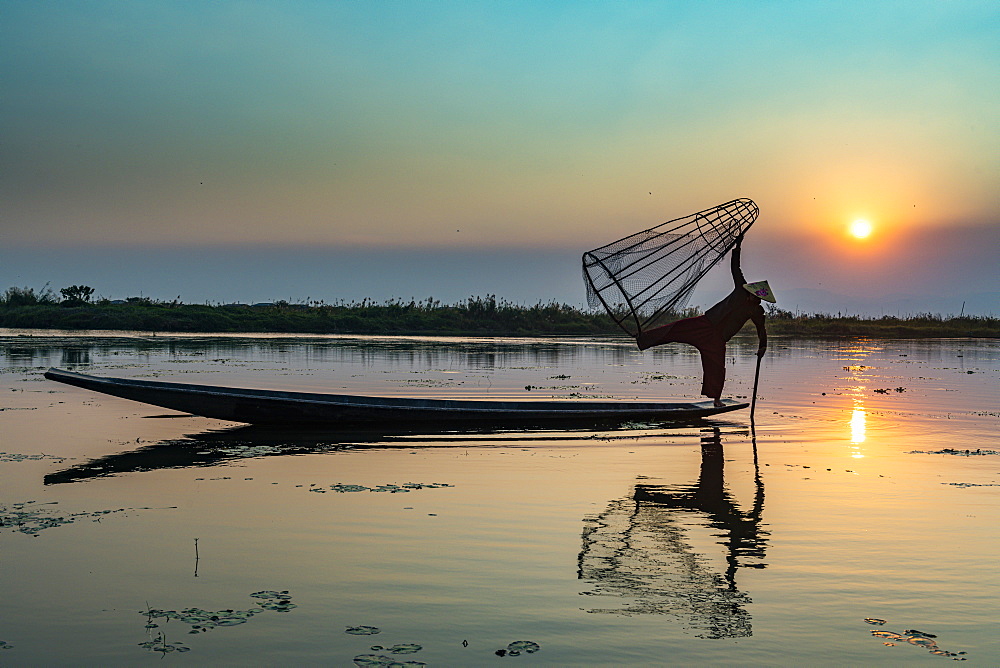 Fisherman at Inle Lake with traditional Intha conical net at sunset, fishing net, leg rowing style, Intha people, Inle Lake, Shan state, Myanmar (Burma), Asia