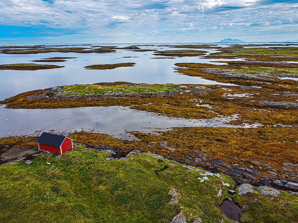 Aerial of a red boat shed on the rugged coastline of the UNESCO World Heritage Site, the Vega Archipelago, Norway, Scandinavia, Europe