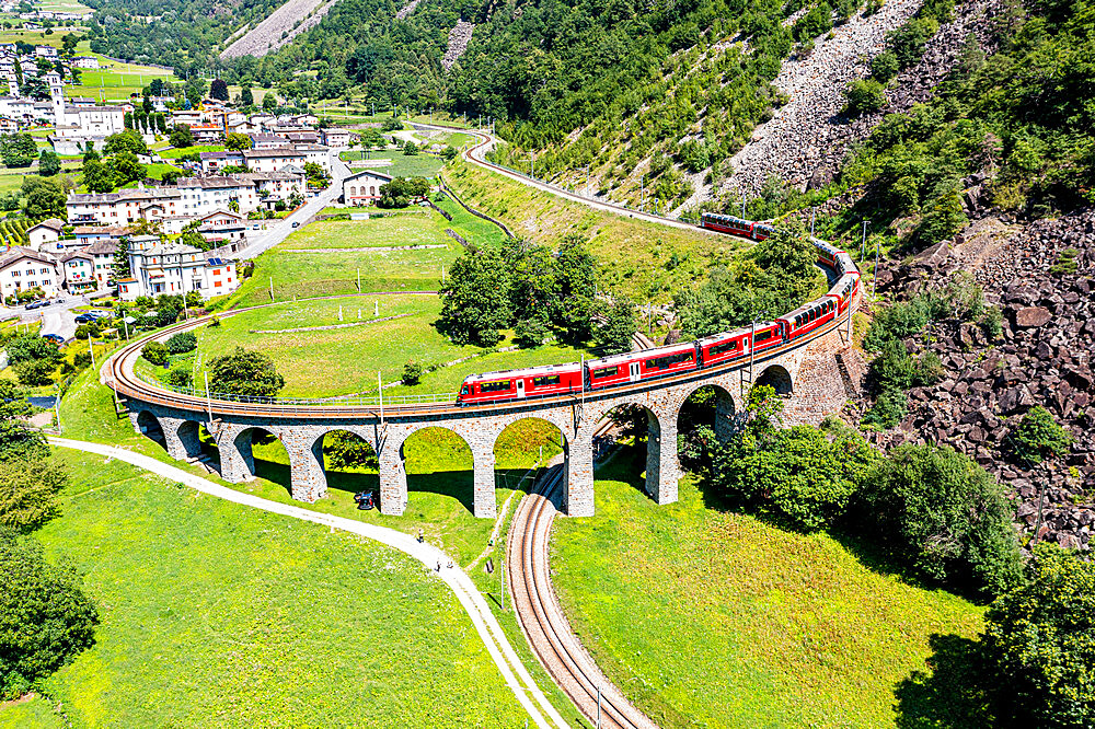 Aerial of a Train crossing the Brusio spiral viaduct, UNESCO World Heritage Site, Rhaetian Railway, Switzerland, Europe