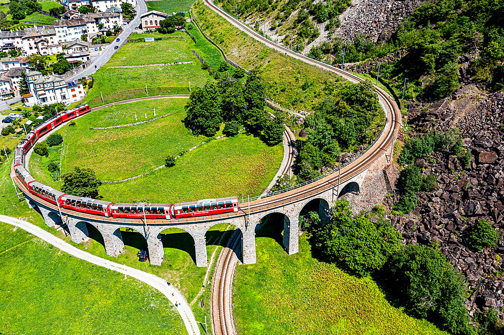 Aerial of a Train crossing the Brusio spiral viaduct, UNESCO World Heritage Site, Rhaetian Railway, Switzerland, Europe