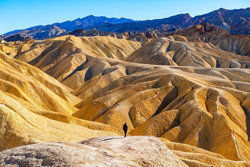 Hiker in the colourful sandstone formations, Zabriskie Point Death valley, California, USA