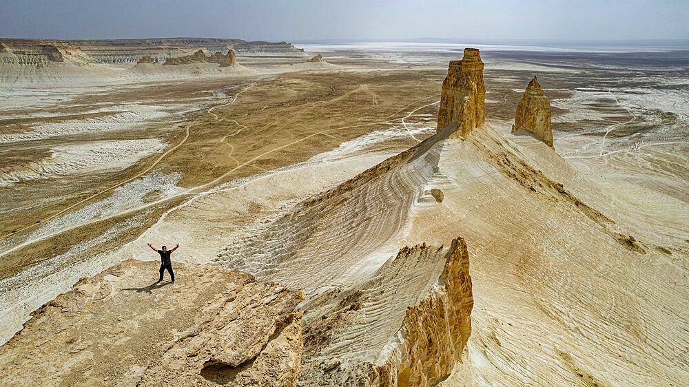 Aerial of a man standing on a cliff, Bozzhira Canyon, Ustyurt plateau, Mangystau, Kazakhstan, Central Asia, Asia