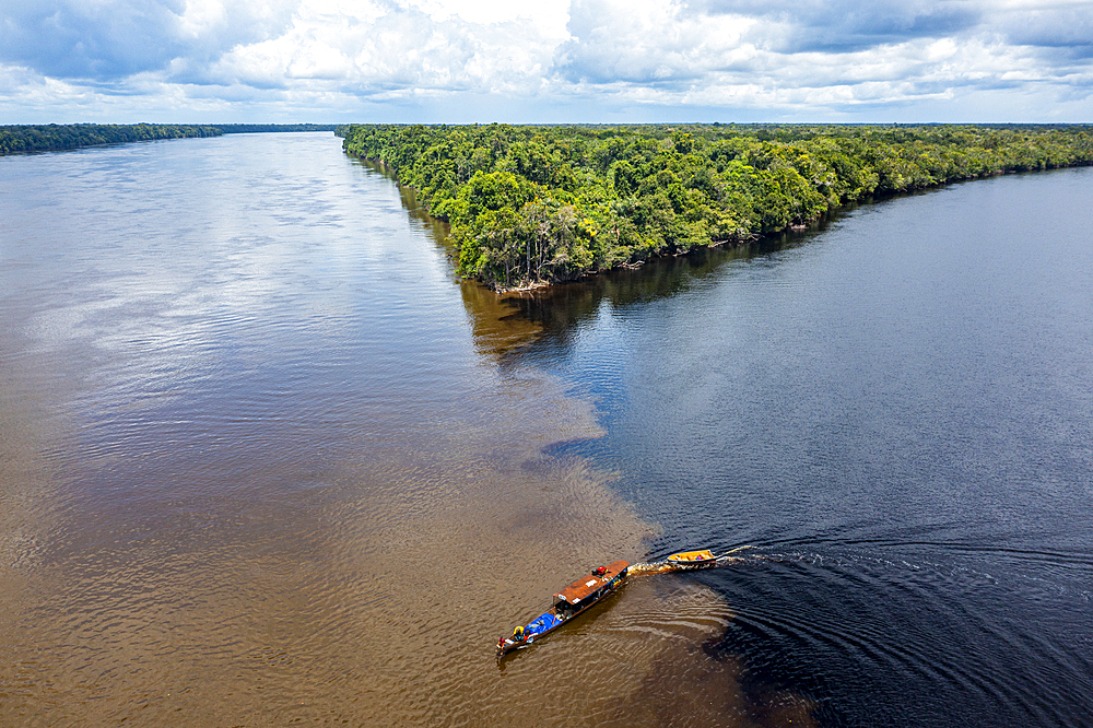 Little boat on the meeting point of the Casiquiare River and black Pasimoni River, in the deep south of Venezuela, South America