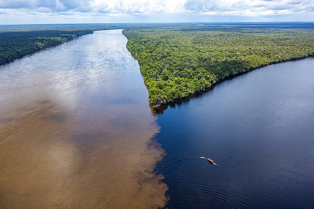 Little boat on the meeting point of the Casiquiare River and black Pasimoni River, in the deep south of Venezuela, South America