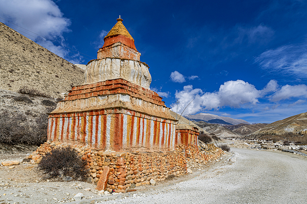 Colourfully painted Buddhist stupa in front of mountain landscape, eroded landscape and houses of Garphu behind, Garphu, Kingdom of Mustang, Himalayas, Nepal, Asia