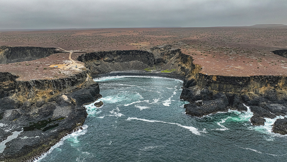 Aerial of the wild coastline with basalt pools on the Atlantic coastline, Dombe Grande, Namibre, Angola, Africa