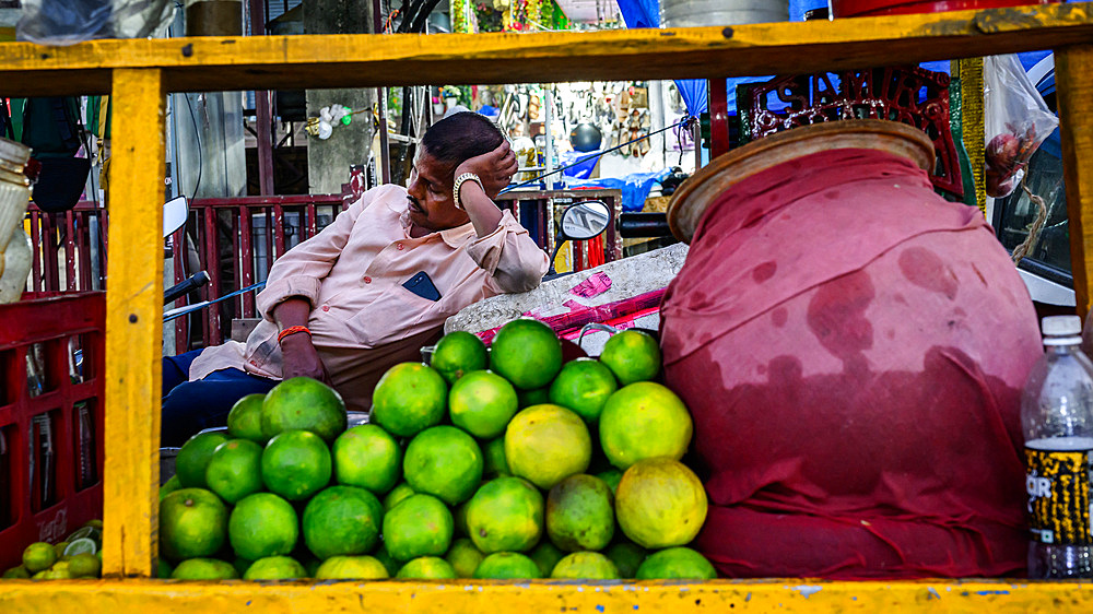 Man resting up  behind his cart of limes, Guwahati, Assam, India, Asia