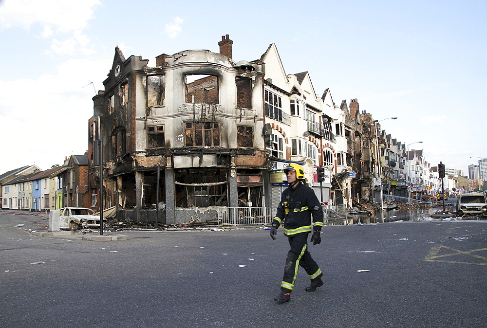 Firefiighter inspects damage to property after riots and looting in Croydon, London, UK ;