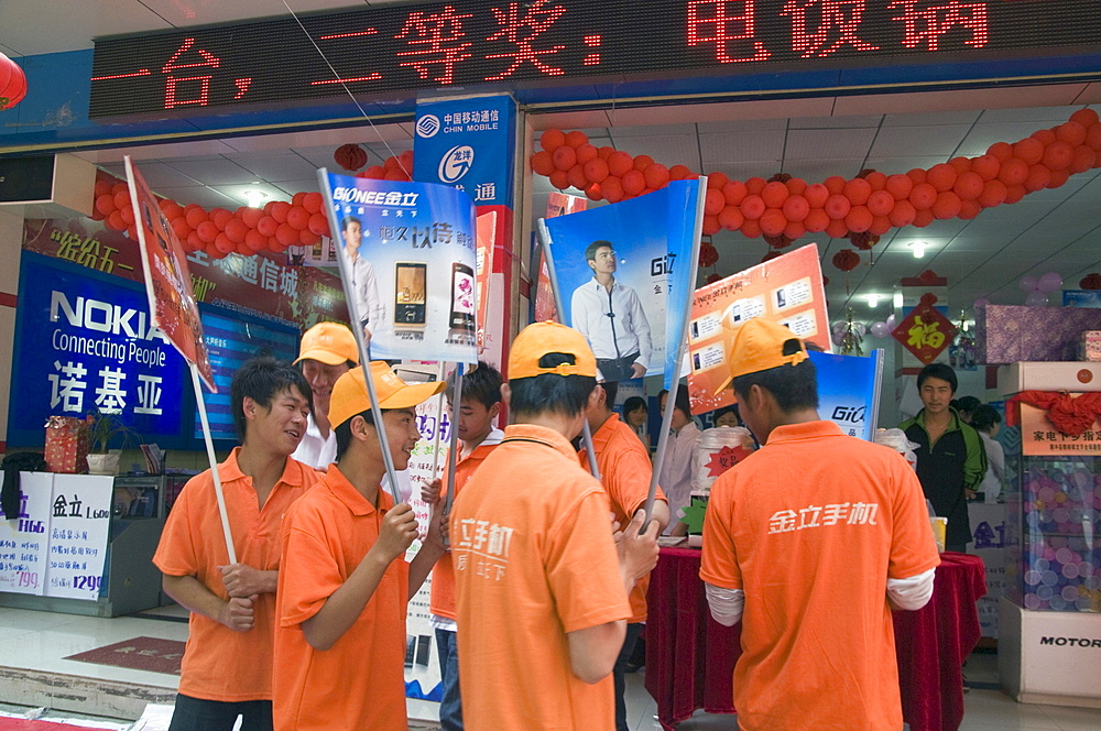 China young men hired to advertise goods outside an electronics shop in kunming, yunnan province