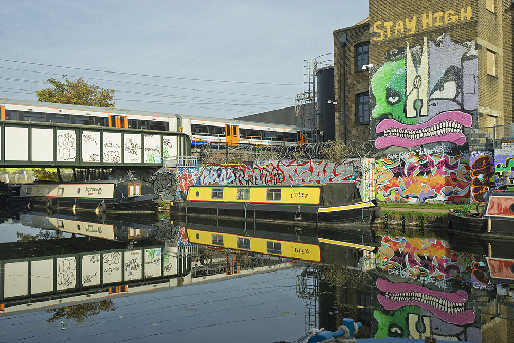 Overground train drives past canal by artists studios and warehouses in Hackney Wick, London, England, United Kingdom, Europe