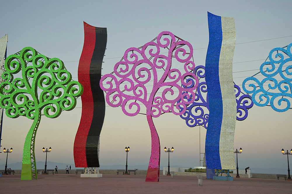 People in the evening by the lakeside malecon, with metal trees illuminated at night, Managua, Nicaragua, Central America