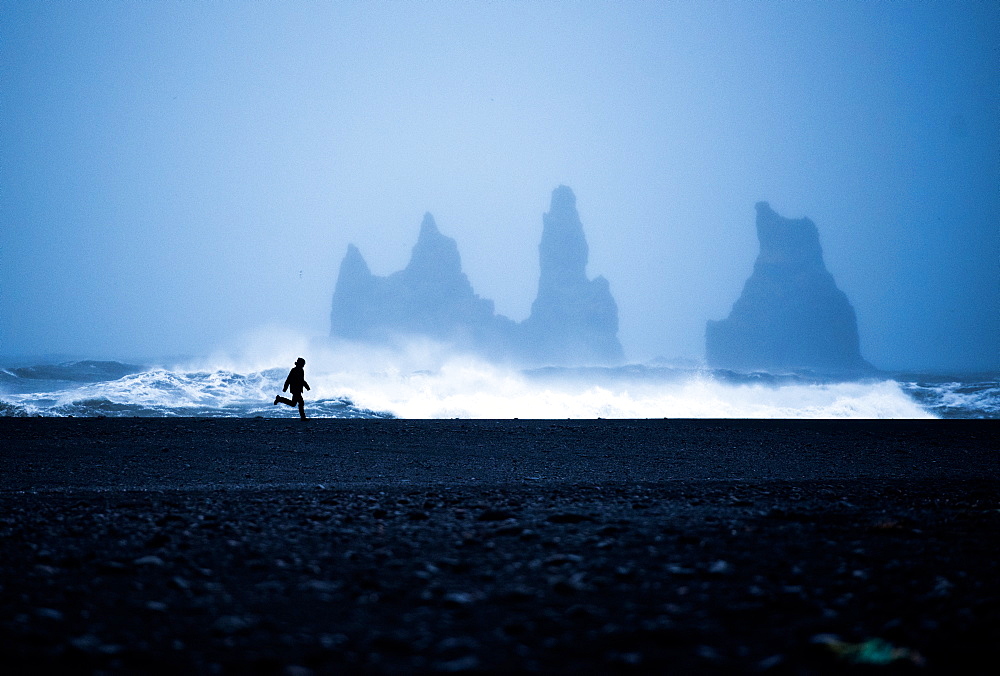 Tourist running on Black Sand Beach, Iceland, Polar Regions