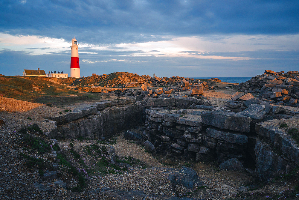 Portland Bill Lighthouse at sunset with remnants of limestone quarry in the foreground, Portland, Dorset, UK